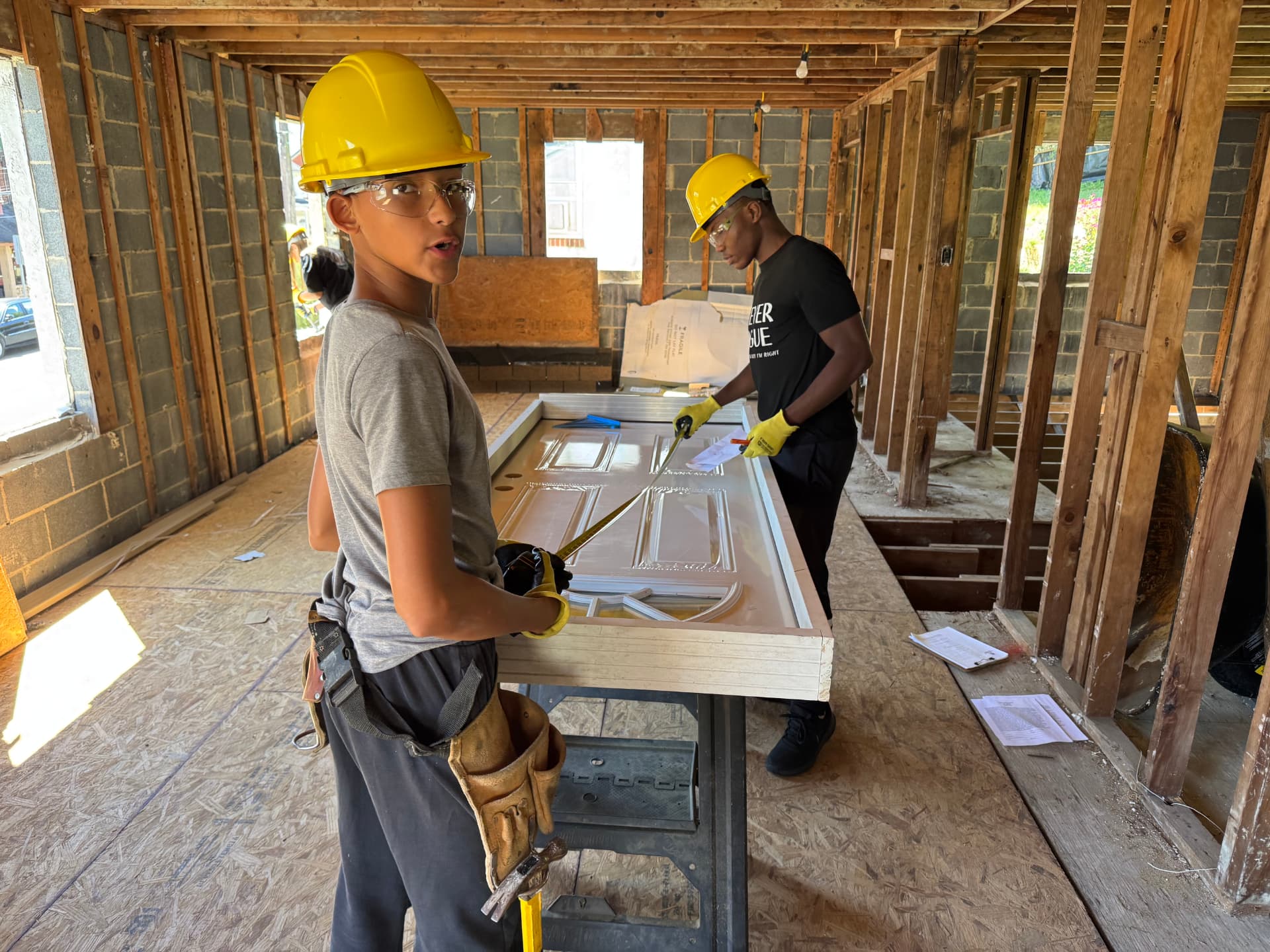 Participants using a tape measure on a door inside a house under renovation