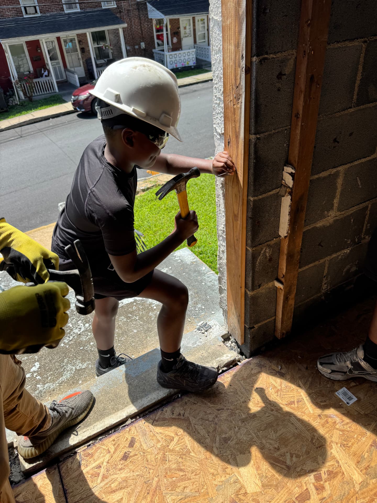 A young participant hammering a nail into a door frame